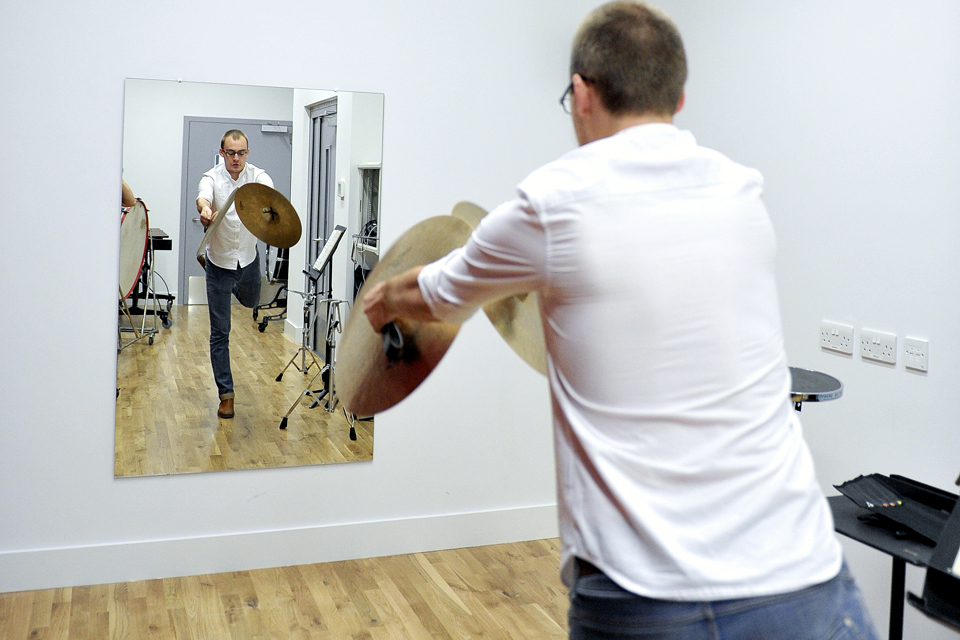 A person playing the cymbals whilst looking in the mirror.